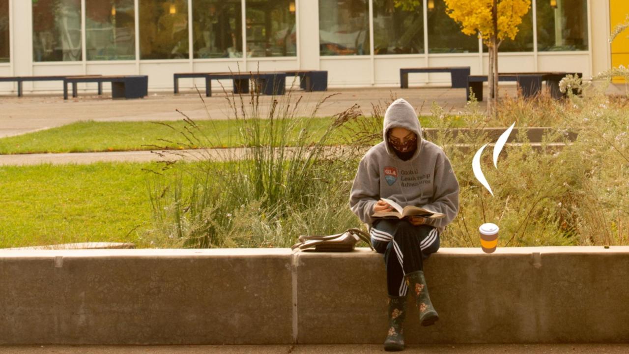 A student reads in front of the Memorial Union next to clip art of a steaming to-go coffee cup