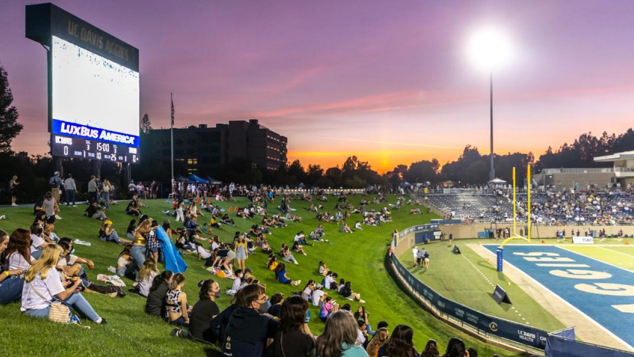 Student watching football game at sunset
