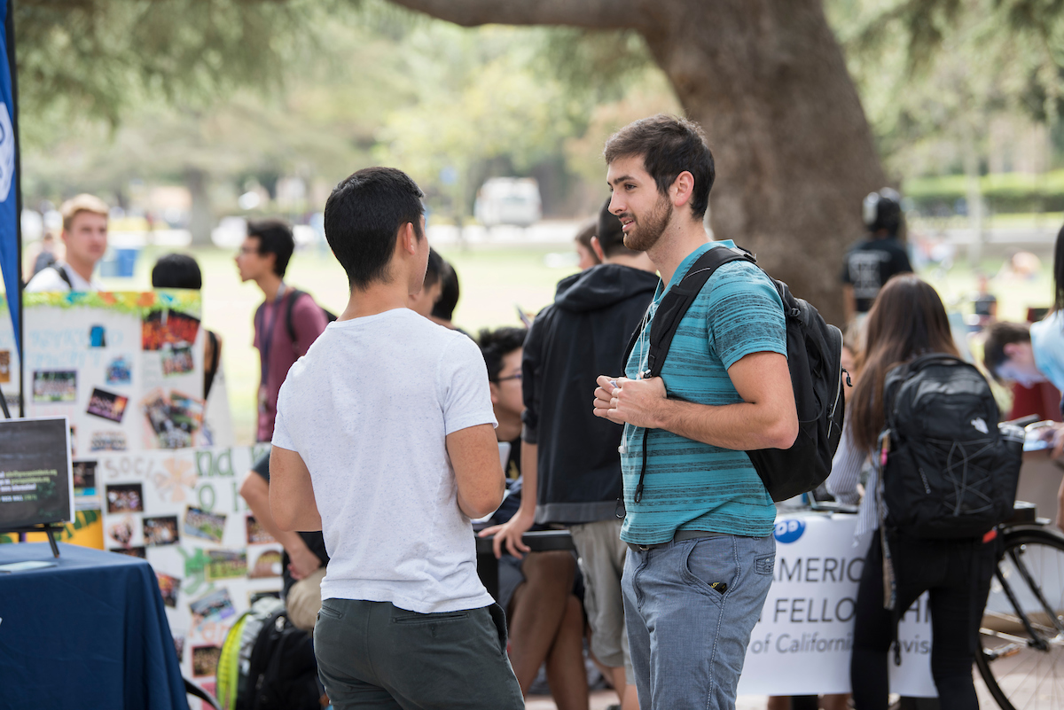 Two students talk to each other in front of student groups tabling near the Memorial Union during Welcome Week 2017 
