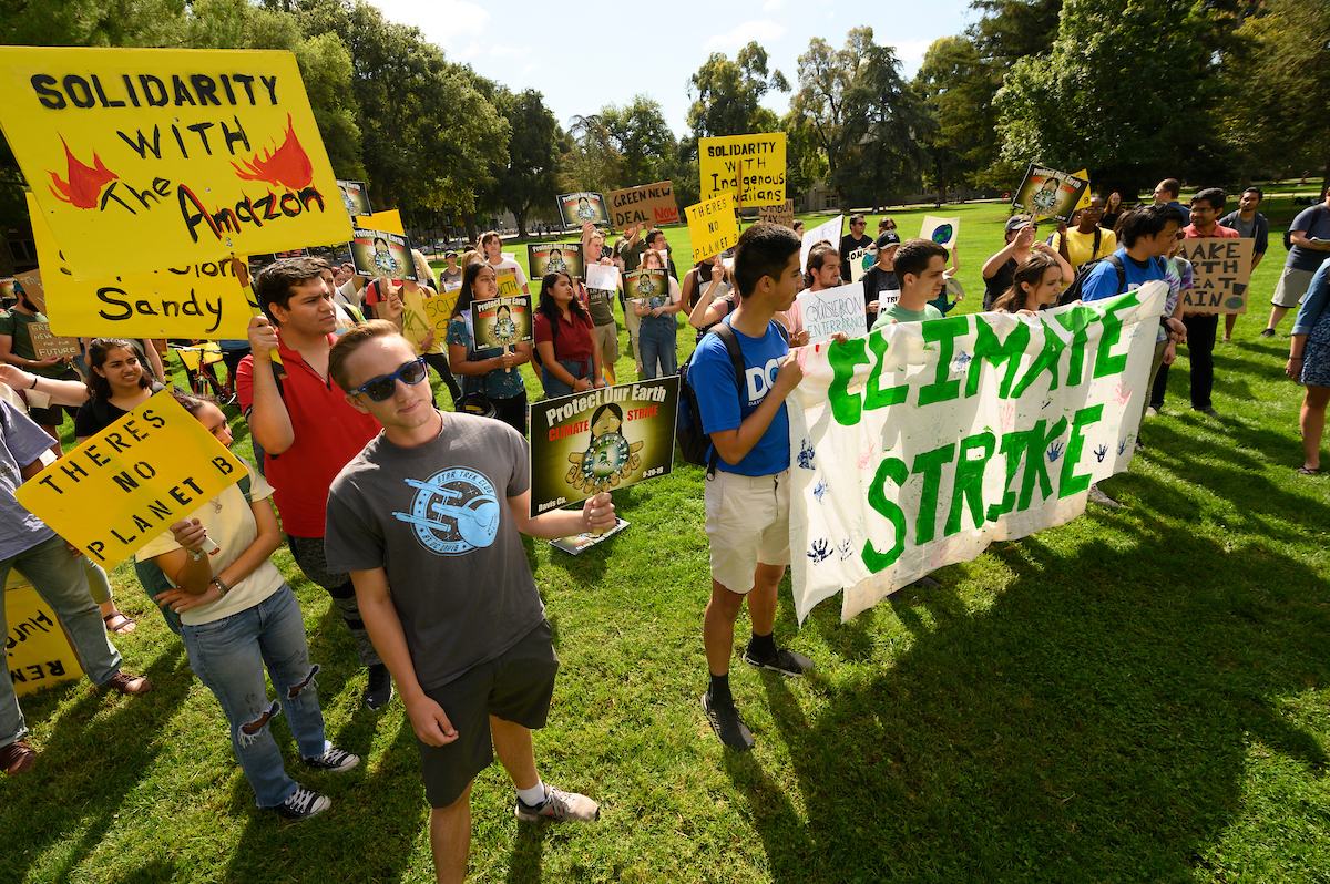 Students gather in the quad and hold signs at a climate protest