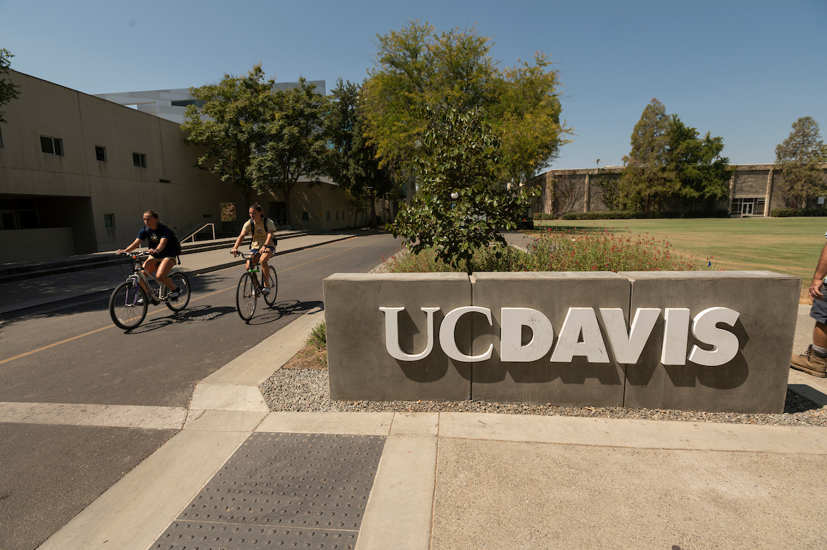 Biking past a UC Davis sign on campus
