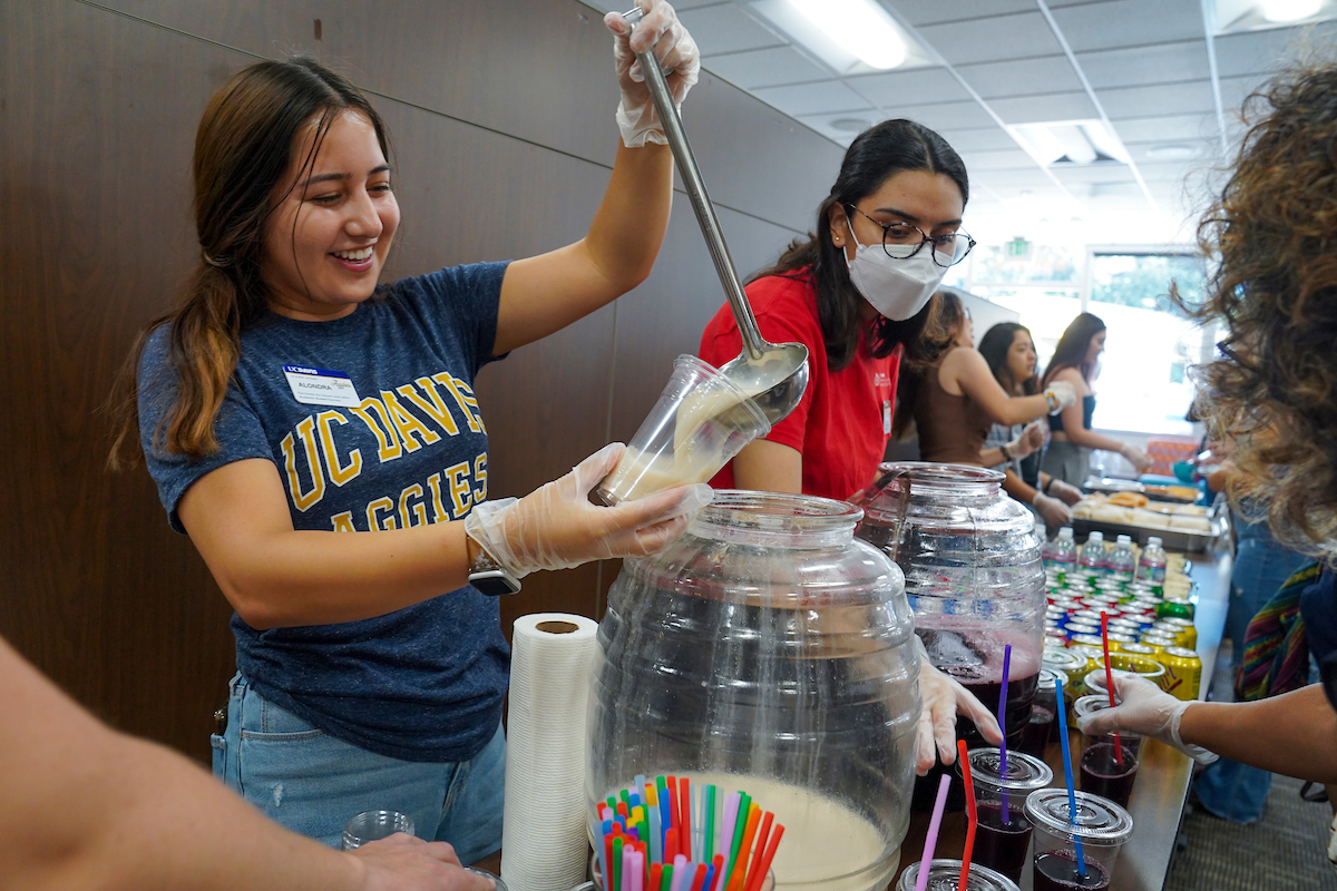 A student pours a drink into a cup at the CCLASS 5th Year Anniversary celebration and open house