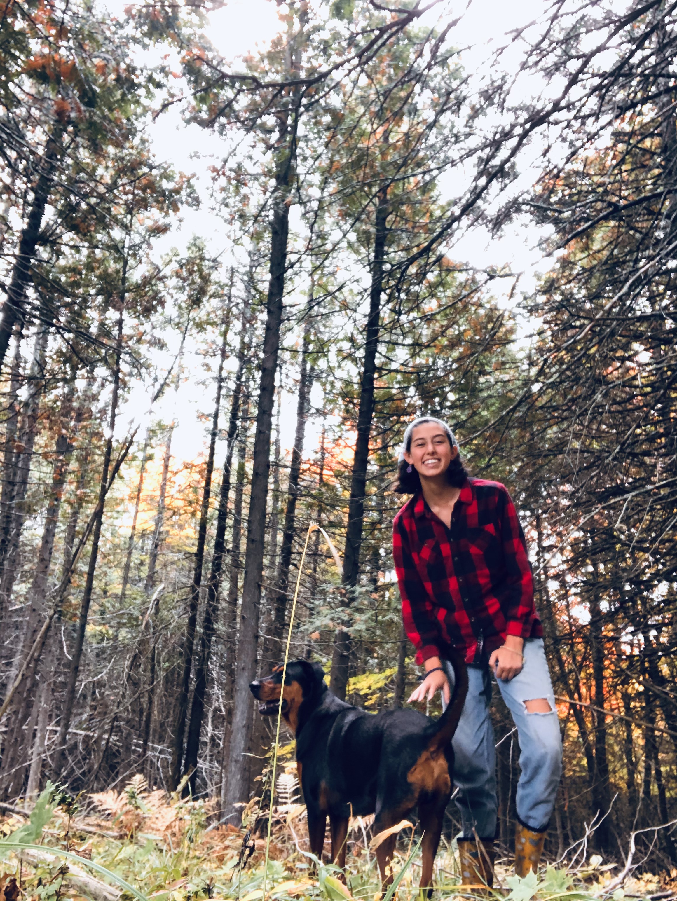 Olivia Rodriguez stands among trees with a dog