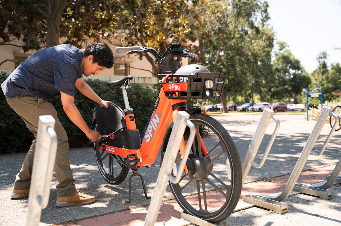 Person locking their Spin bike to a campus bike rack.