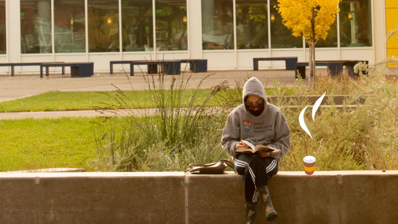 A student reads in front of the Memorial Union next to clip art of a steaming to-go coffee cup