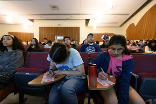 A class of students take a scantron test in a lecture hall
