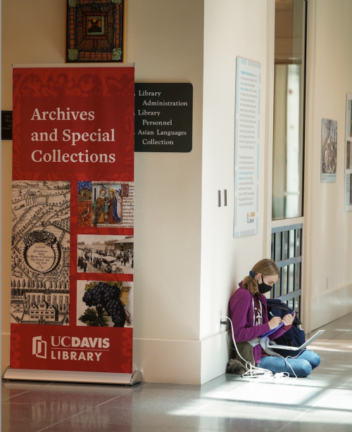 Student sitting near Archives and Special Collections sign